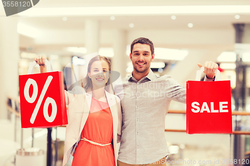 Image of happy young couple with red shopping bags in mall