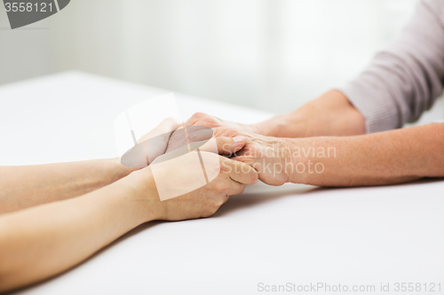 Image of close up of senior and young woman holding hands