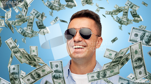 Image of happy man in sunglasses with falling dollar money