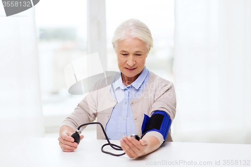 Image of old woman with tonometer checking blood pressure