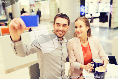 Image of happy couple with smartphone taking selfie in mall