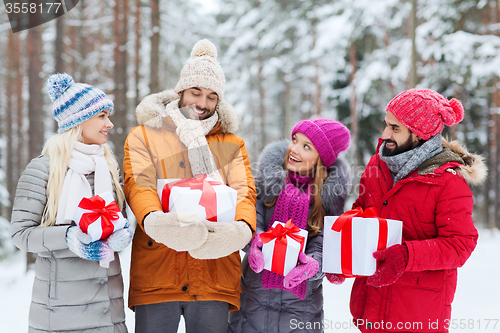 Image of happy friends with gift boxes in winter forest