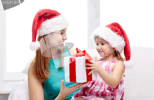 Image of happy mother and child in santa hats with gift box