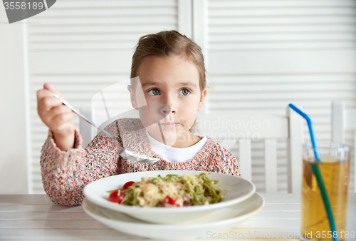 Image of little girl eating pasta for dinner at restaurant