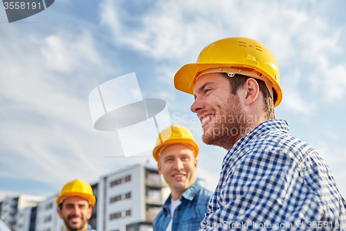 Image of group of smiling builders in hardhats outdoors