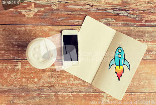 Image of close up of notebook, coffee cup and smartphone