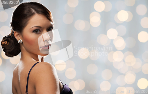 Image of woman with diamond earring over holidays lights