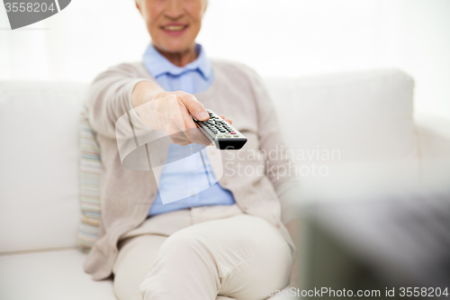 Image of close up of happy senior woman watching tv at home