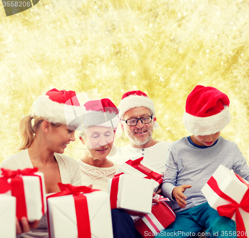 Image of happy family in santa helper hats with gift boxes