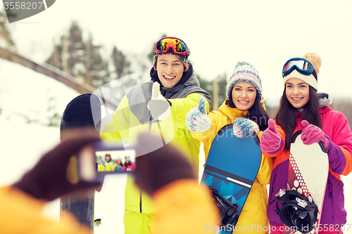 Image of happy friends with snowboards and smartphone