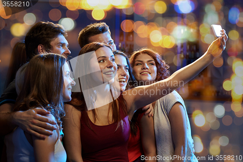 Image of friends with smartphone taking selfie in club