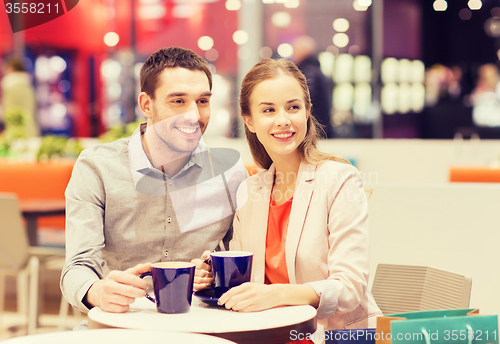Image of happy couple with shopping bags drinking coffee