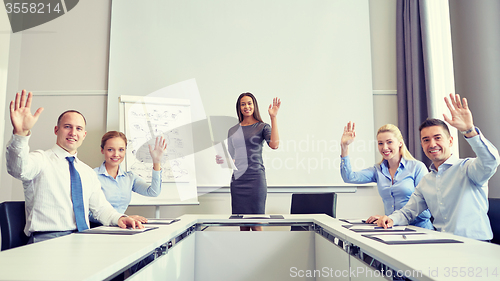 Image of group of businesspeople waving hands in office