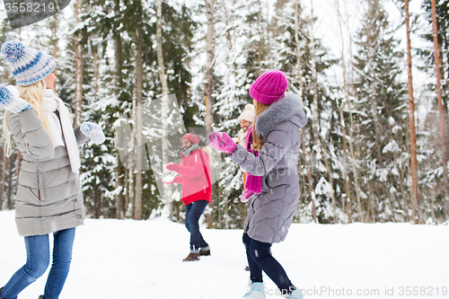 Image of happy friends playing snowball in winter forest