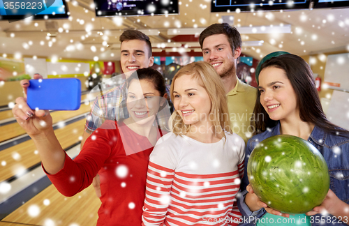 Image of happy friends with smartphone in bowling club