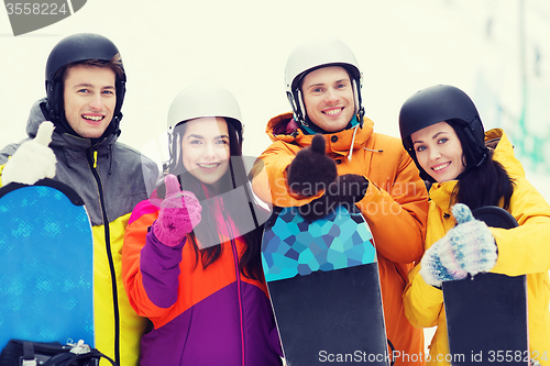 Image of happy friends in helmets with snowboards