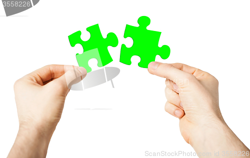 Image of close up of male hands with green puzzle pieces