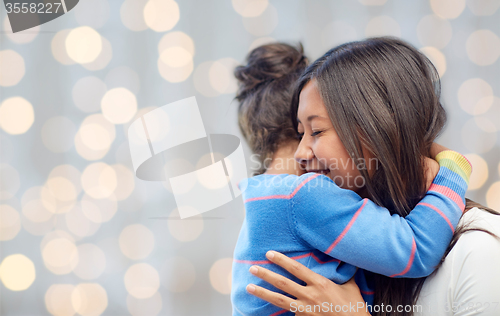 Image of happy mother and daughter hugging over lights