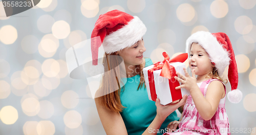 Image of happy mother and child in santa hats with gift box