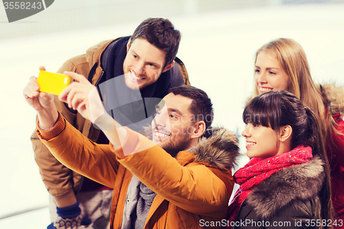 Image of happy friends with smartphone on skating rink