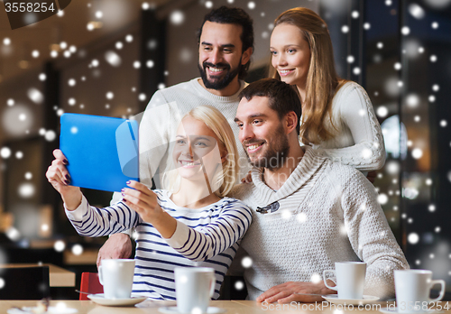 Image of happy friends with tablet pc taking selfie at cafe