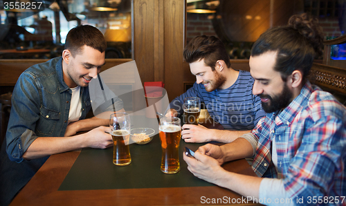 Image of male friends with smartphones drinking beer at bar