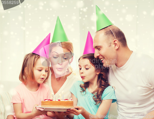 Image of happy family with two kids in party hats at home