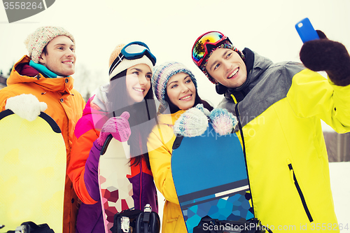 Image of happy friends with snowboards and smartphone