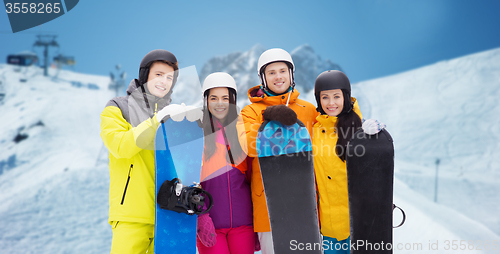 Image of happy friends in helmets with snowboards outdoors