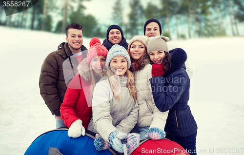 Image of smiling friends with snow tubes and selfie stick