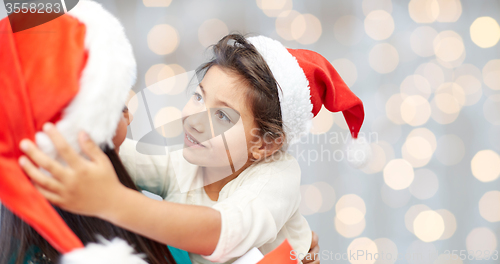 Image of happy mother and little girl in santa hats