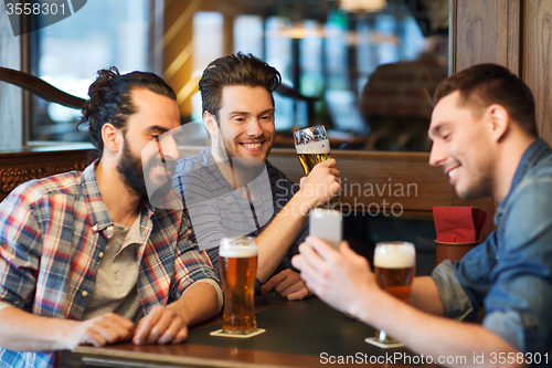 Image of male friends with smartphone drinking beer at bar