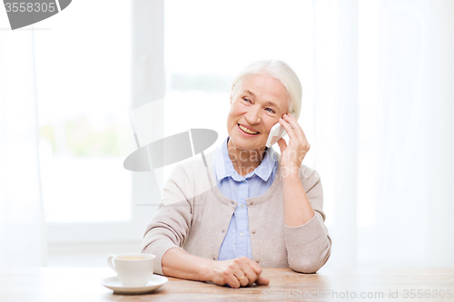 Image of senior woman with smartphone calling at home