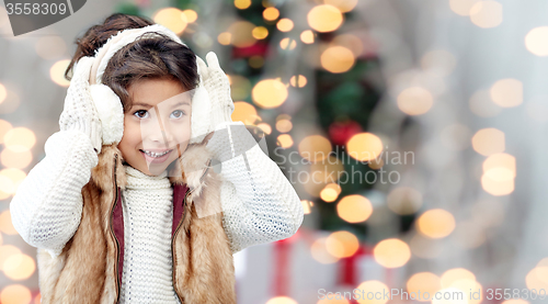 Image of happy little girl wearing earmuffs at christmas