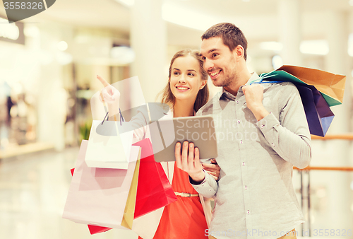 Image of couple with tablet pc and shopping bags in mall