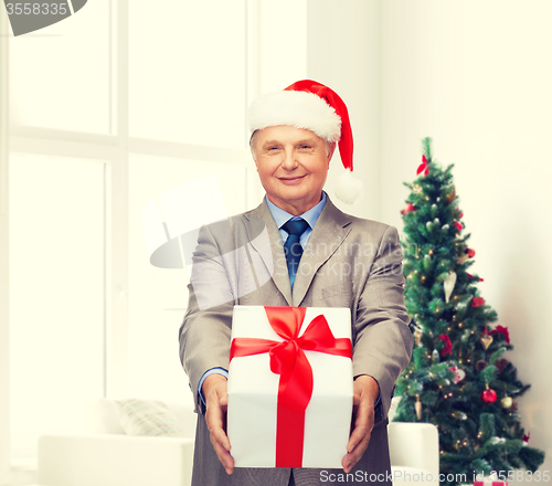 Image of smiling man in suit and santa helper hat with gift