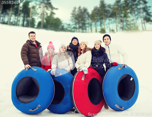 Image of group of smiling friends with snow tubes