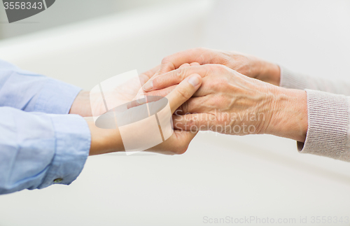 Image of close up of senior and young woman hands