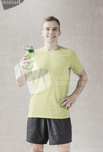 Image of smiling man with bottle of water in gym
