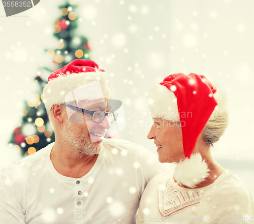 Image of happy senior couple in santa helper hats at home