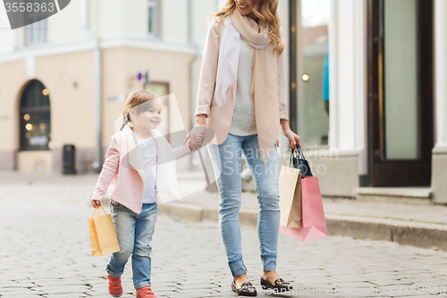 Image of happy mother and child with shopping bags in city