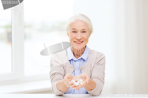 Image of happy senior woman with medicine at home