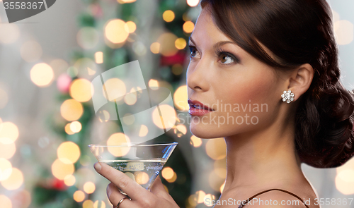 Image of woman face with cocktail over christmas lights