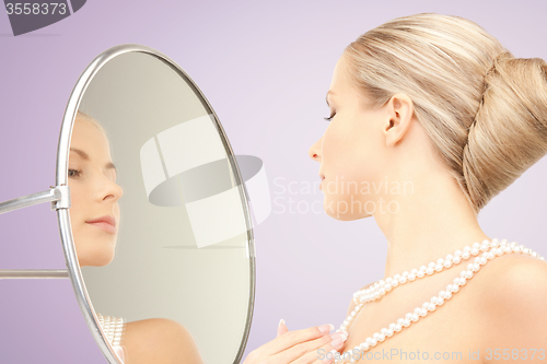 Image of beautiful woman with pearl necklace and mirror