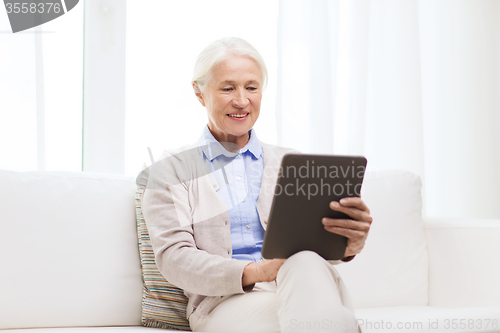 Image of happy senior woman with tablet pc at home