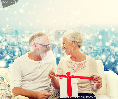 Image of happy senior couple with gift box at home