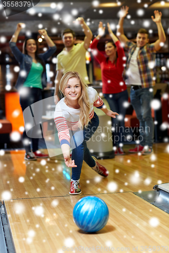 Image of happy young woman throwing ball in bowling club