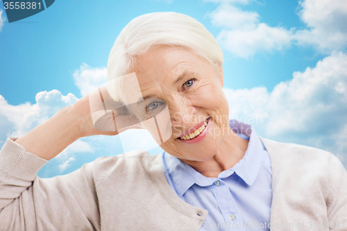 Image of happy senior woman over blue sky and clouds