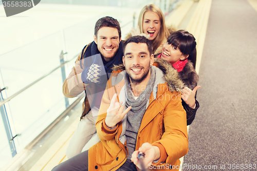 Image of happy friends taking selfie on skating rink