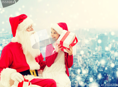 Image of smiling little girl with santa claus and gifts